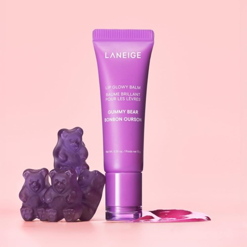 Lila Tube mit dem Label 'Laneige Lip Glowy Balm', drei lila Gummibärchen und Lippenbalsam-Vertropfung.