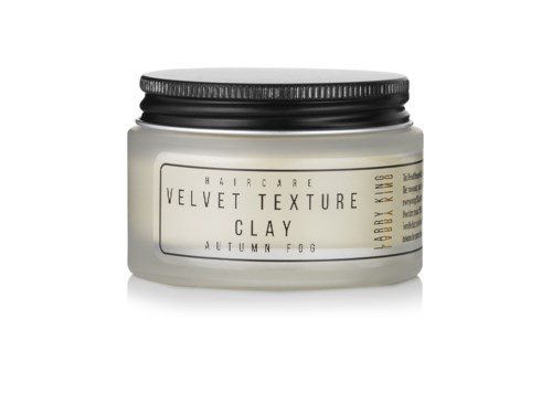 En burk märkning för hårvård kallad Velvet Texture Clay, doft av höstdimma, med svart lock.