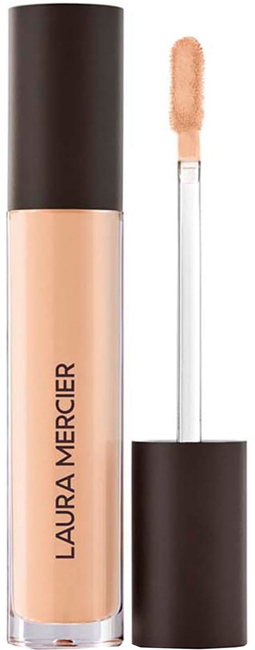 En beige flytande concealer i en flaska med svart lock och applikatorstav.