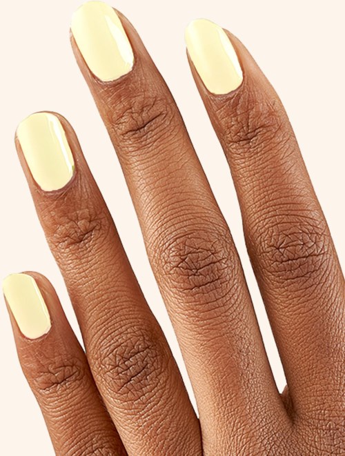 Hand with yellow painted nails against a light background.