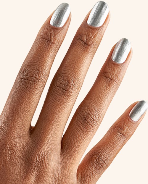 Hand med silvermålade naglar på en beige bakgrund. Nära bild av välskötta fingrar.