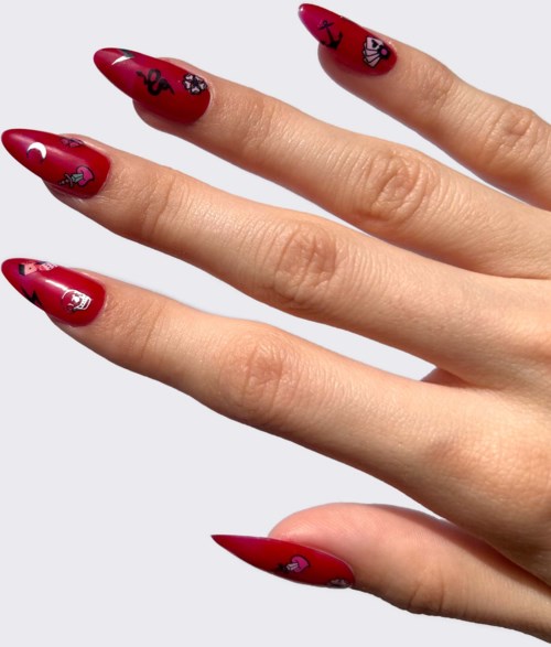 Nail polish with red color and small black and white drawings of skulls and hearts.