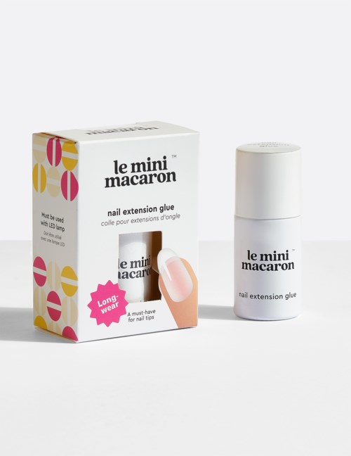 Nail extension glue in a small white bottle next to a colorful box labeled 'le mini macaron' with pink, yellow, and white design.