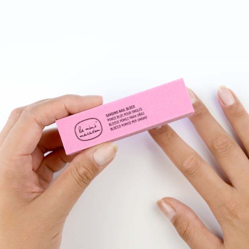En hand håller en rosa nagellacksborttagare med text och en logotyp på.