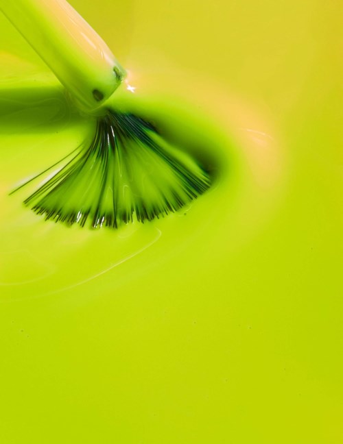 A green paintbrush is painting black lines on a light green background.