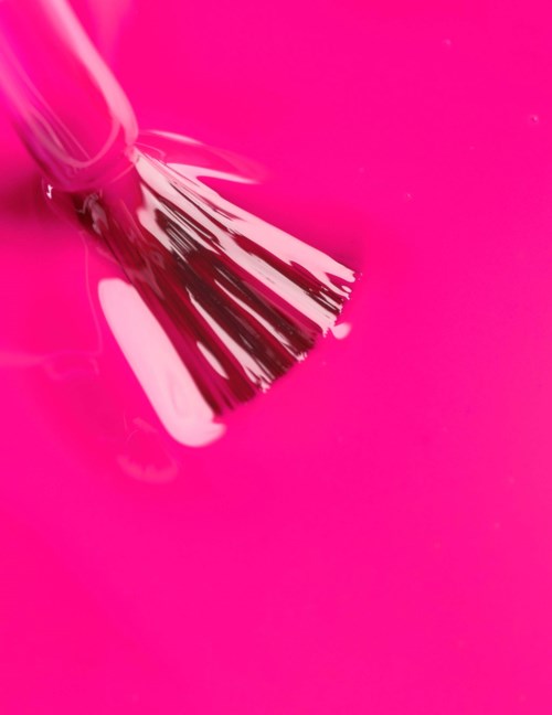 A silver brush with black and white bristles on a pink background.