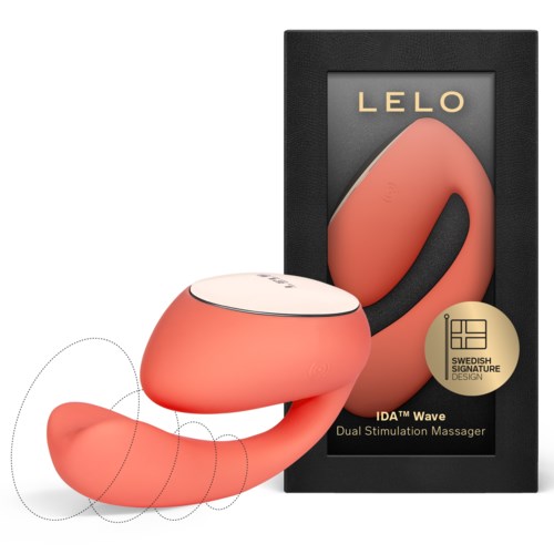 Een perzikkleurige duale stimulatiemassager, gevormd als een gebogen 'S', met zwarte handgreep en doosverpakking.