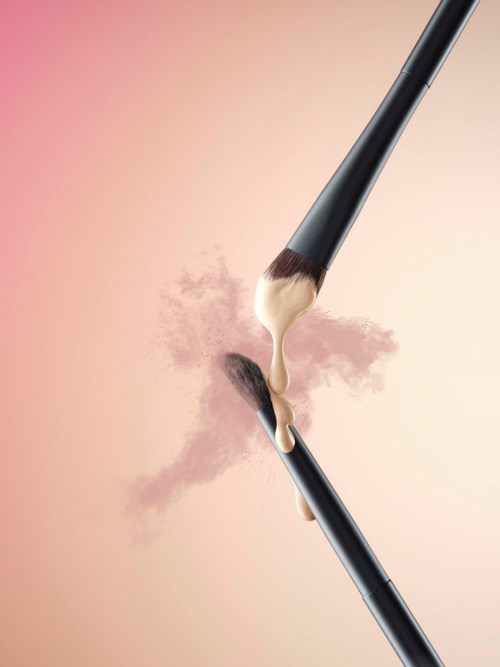Twee make-up borstels met poeder en crème die in het midden versmelten op een roze achtergrond.