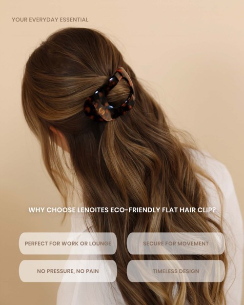 A woman with long, wavy hair uses a tortoiseshell flat hair clip to gather part of her hair. The background is plain.