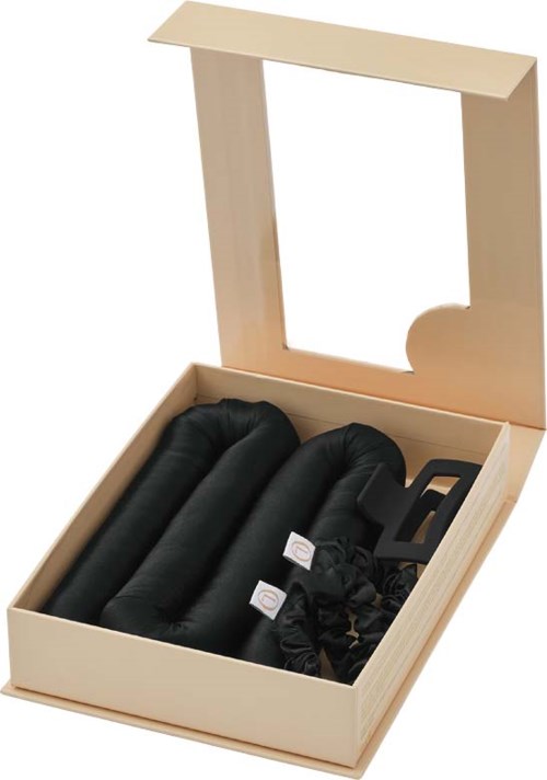 Eine Holzschachtel enthält drei schwarze Nackenstützen und Zubehör, mit einem geöffneten transparenten Deckel.