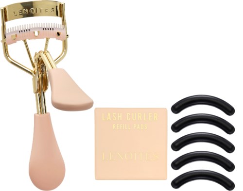 Ein rosa und goldener Wimpernformer, Nachfüllpads und vier schwarze falsche Wimpern. Grundlegende Schönheitstools für Augen Make-up.