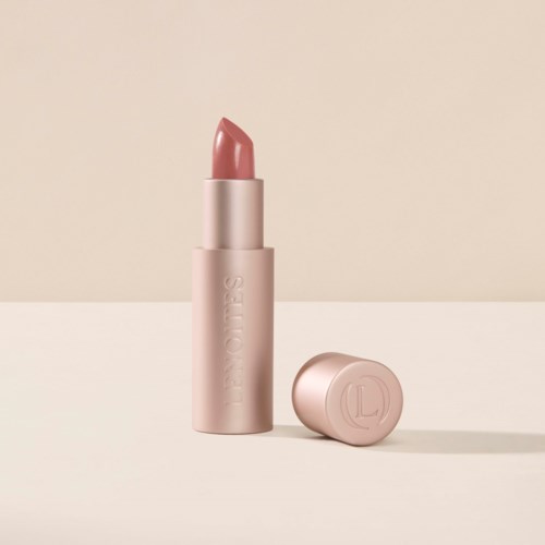 Ett rosa läppstift med lock, står på en beige bakgrund. Läppstiftet är något vridet och visar produkten.