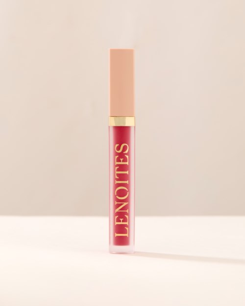 En tube med rosa leppepomade med beige lokk og gullkant, merket "L'ENOTE" i gullbokstaver.