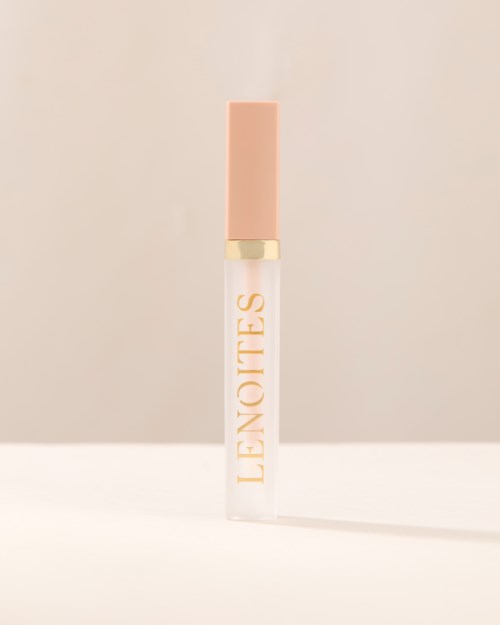 En klar leppeglansflaske med rosa lokk og ordet "LENOTES" skrevet vertikalt på den.