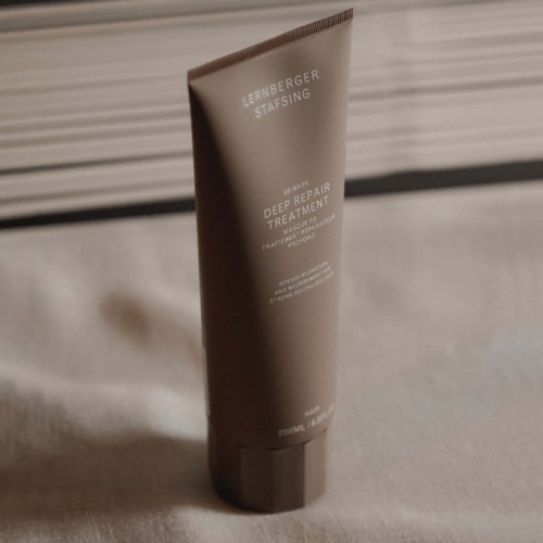 A brown tube of Lernberger Stafsing Deep Repair Treatment with white text, placed on a beige surface.