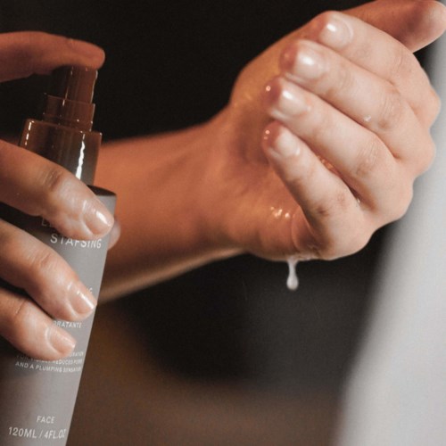 A person applies liquid from a bottle onto their hand, likely for cleaning or skincare.