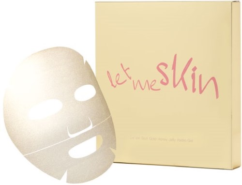 En ansiktsmask liggande framför en beige låda med rosa text som säger 'let me skin'.