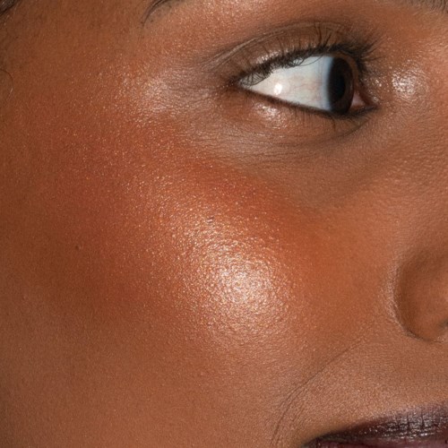 Close-up van iemands wang die glimlach, met soepele, gloeiende huid en deel van het oog en de lippen.