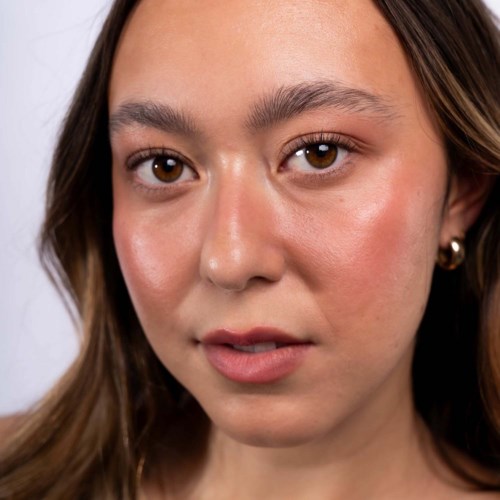 Een jonge vrouw met lichte huid, bruin haar en bruine ogen kijkt recht naar de camera. Ze heeft natuurlijke make-up en kleine oorbellen.