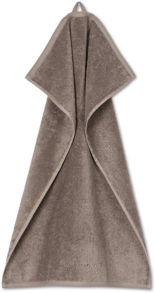 En beige mjuk handduk hängande med huva upptill och kanter vikta. Den ser varm och skön ut.