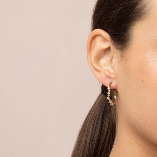 Close-up of a woman's ear with a gold hoop earring and brown hair.