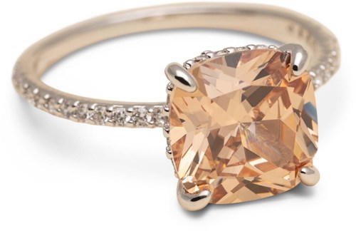 Einen Ring mit einem großen pfirsichfarbenen Edelstein und kleinen klaren Steinen am Band.
