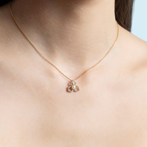 En kvinna bär ett fint halsband med ett litet, elegant fjärilsmykke prytt med ädelstenar.