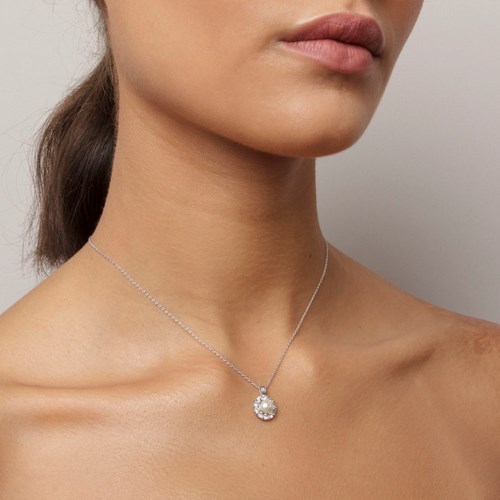 En kvinna bär ett halsband med en stor, glittrande sten hängande, visar hennes nacke och axlar.