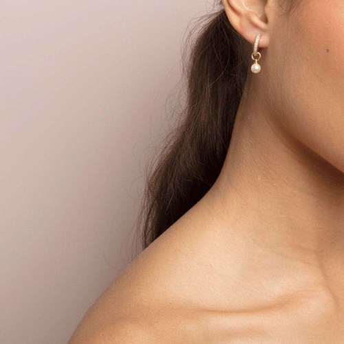 The image shows a woman's shoulder, part of her face, and a pearl earring.