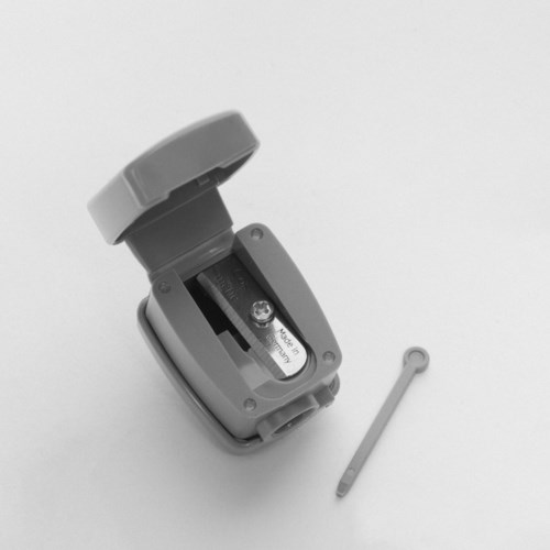En liten, öppen plastbehållare med ett batteri inuti och ett separat plant verktyg.