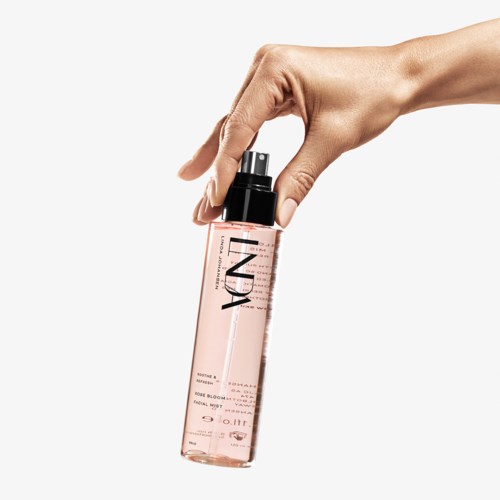 En hånd holder en rosa sprayflaske merket 'NDA', med svart lokk og spraymunnstykke.