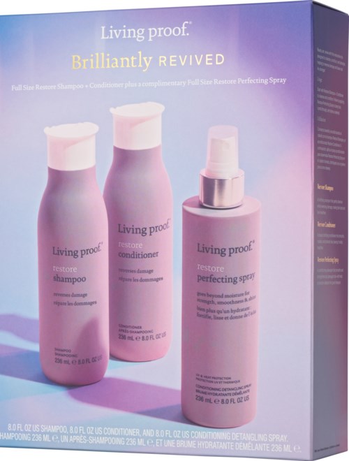 Three pink bottles with white caps for shampoo, conditioner, and spray on a purple background. The brand is Living Proof.