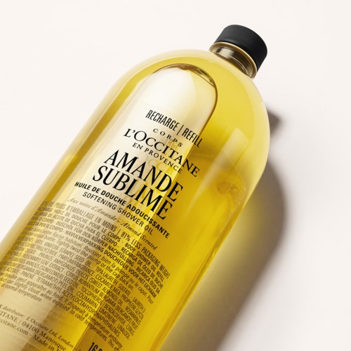 Gul flaske med L'Occitane Amande Sublime showerolie med sort låg og detaljeret etikette.