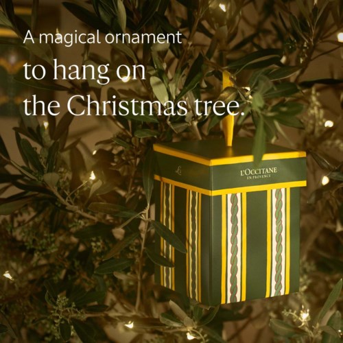 En randig gul och grön box hänger på julgranen som prydnadsdekoration.