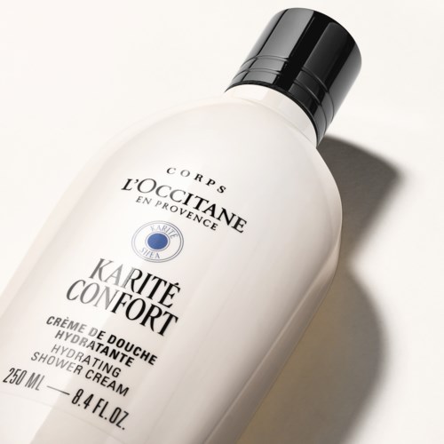 En hvit dusjsåpeflaske med svart lokk, merket 'L'OCCITANE Karité Confort', 250 ml, viktige elementer av fukt og komfort.