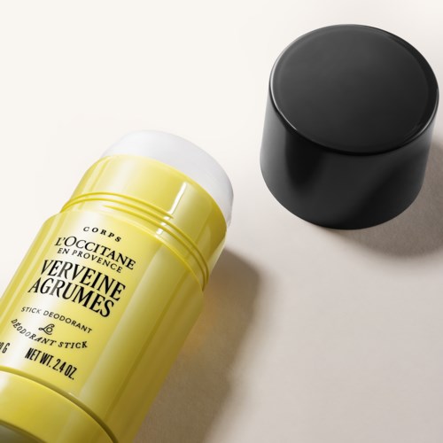 Żółty sztyft dezodorantu z czarną nakrętką, oznaczony L'Occitane Verveine Agrumes, na jasnej powierzchni.