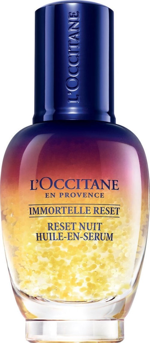 En serumflaska med mörkblå kork och färgövergång från lila till gult, märkt "L'OCCITANE IMMORTELLE RESET."