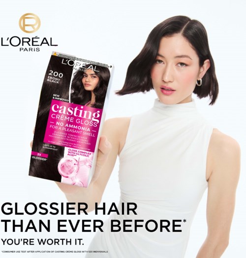En kvinna med kort svart hår håller en L'Oréal casting hårfärgningsbox, bär en vit topp, med L'Oréal-logotypen i hörnet.