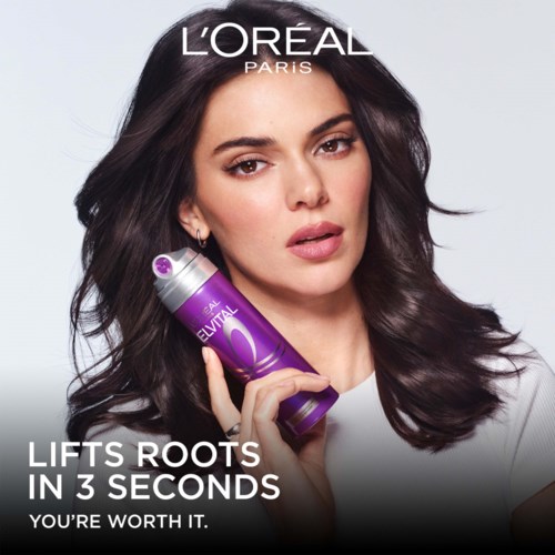 En kvinne med mørkt hår holder en lilla flaske, med tekst om L'Oréal Paris hårpleiefordeler.