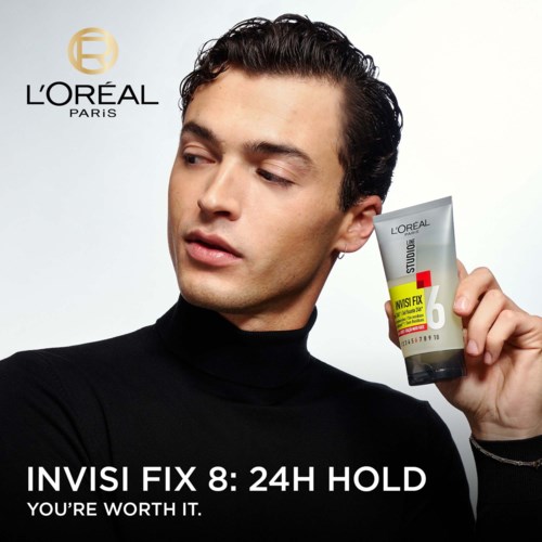 Ein Mann in Schwarz hält eine Tube eines L'Oréal-Produkts, mit Logo und Text im Hintergrund, fördert Haarstyling.
