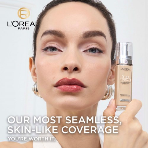 A woman with makeup holds a foundation bottle, with L'Oréal logo and text about makeup coverage. Bright background.