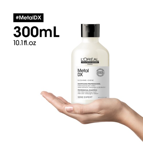 Käsivarsi pitää kädessä L'Oréal Metal DX ammattihampoota, valkoinen tausta ja musta teksti. Koko 300mL.