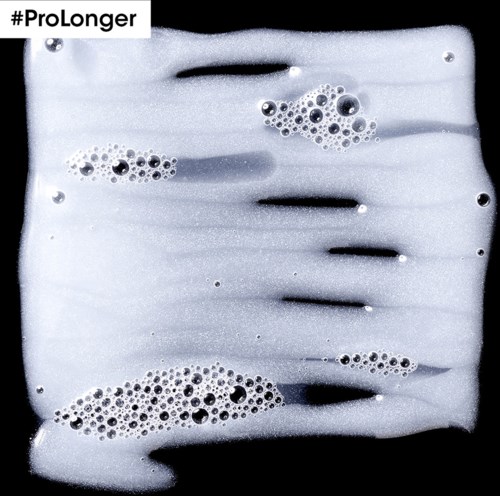 Skumiga bubblor flyter på en vätskeuppsättning med mörka streck, märkt #ProLonger.