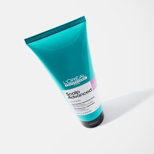 Sininen L'Oréal päänahan hoitotuoteputki valkoisella, mustalla ja violetilla värillä seisoo valkoisella pinnalla.