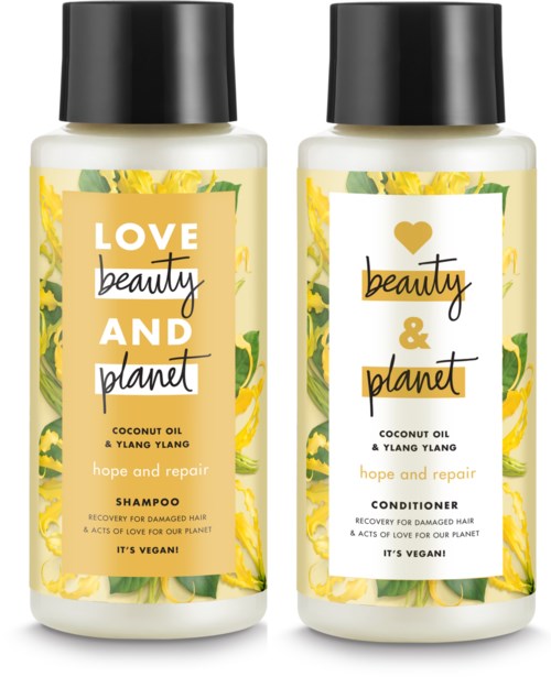 Två flaskor från Beauty and Planet med kokosolja och Ylang Ylang schampo och balsam med gula blommor.