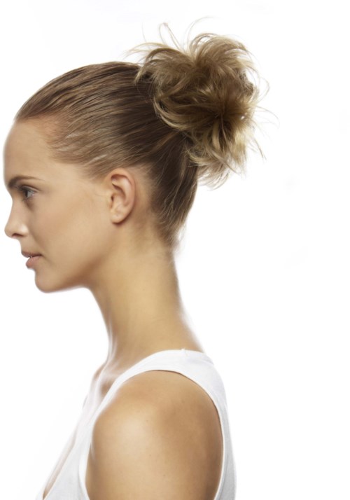 A woman with blonde hair in a messy bun, wearing a white sleeveless top, facing left, against a white background.