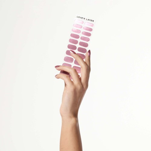 En hand håller en palett med nagellack i rosa nyanser, från ljust till mörkt.