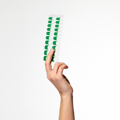 En hånd holder en stripe med 14 grønne og hvite medisinske blisterpakker. Pakken har mest brukte piller.
