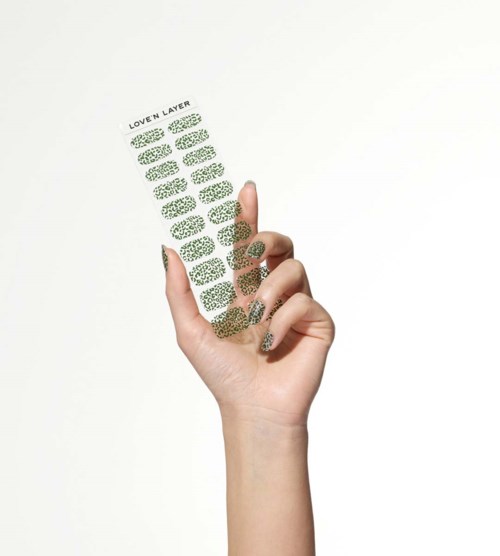 Eine Hand hält ein transparentes Objekt mit mehreren grünen Blättern und Text 'LOVEN LAYER' auf der Oberseite.