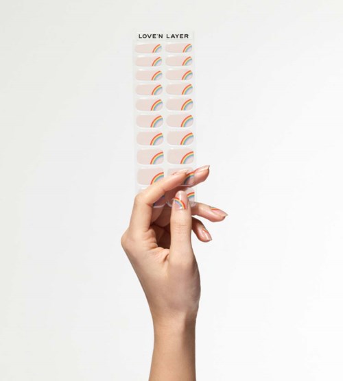 En hånd holder et ark med regnbue-design og teksten 'LOVE'N LAYER' øverst.